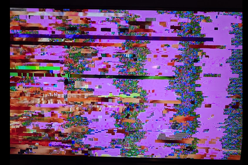 Image of a computer monitor that is completely glitched out and illegible, with some vertical static bands and horizontal blocks of color.